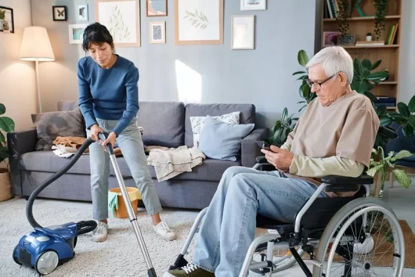 housekeeper-cleaning-the-room-of-senior-man-Keeping-It-Clean