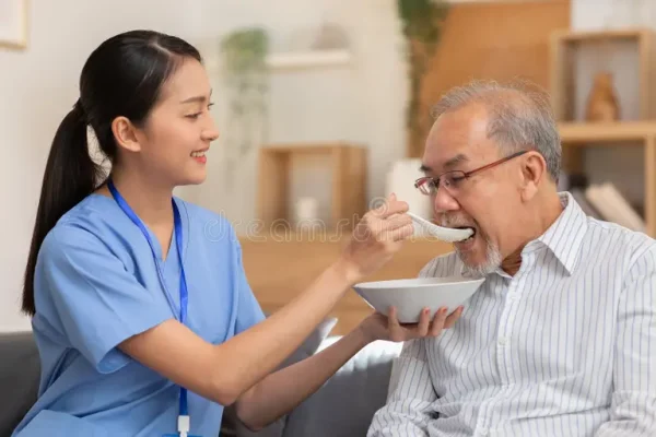 young-asian-nurse-feeding-breakfast-to-senior-man-couch-old-white-beard-enjoy-his-meal-caregiver-take-care-give-soft-244763750
